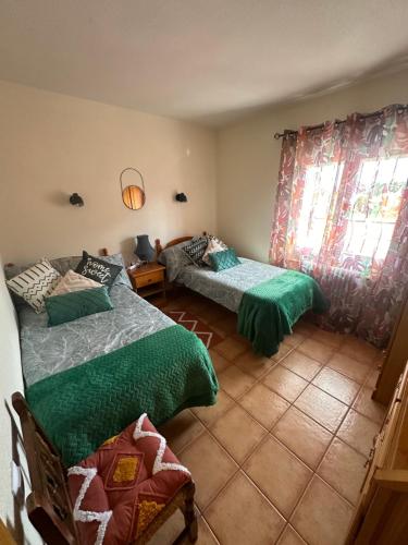 a bedroom with two beds with green comforters at Casas Rurales La Picotilla y la Guija in Martiherrero