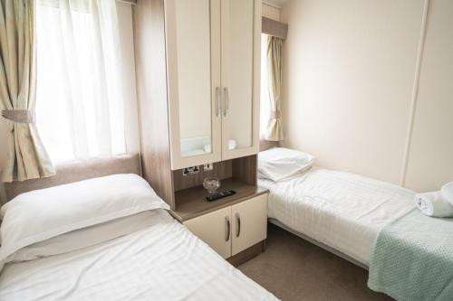 a bedroom with two beds and a cabinet and a window at Marine Holiday Park in Rhyl