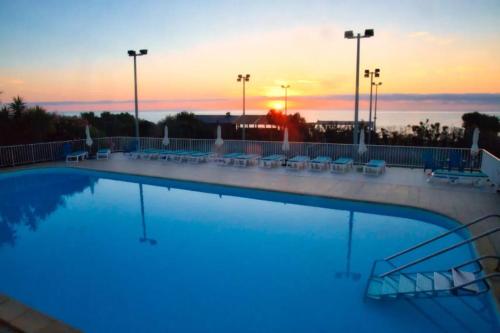 une grande piscine avec un coucher de soleil en arrière-plan dans l'établissement Studio charmant à Cervione avec piscine partagée - 30 m², à Cervione