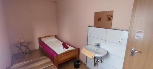 a small room with a small bed and a sink at Alb Rooms, Zimmer auf der Schwäbischen Alb in Oberlenningen