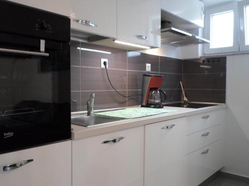 a kitchen with white cabinets and a sink at Apartment Center Njivice in Njivice