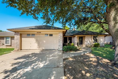 une maison avec un garage et un arbre dans l'établissement Cowboy Chic, à Watauga