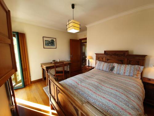 a bedroom with a large bed and a desk at Casa do Cuco, acolhedora, em aldeia tranquila com espaço exterior generoso perto de Pombal in Pombal