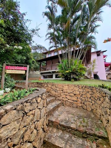 a resort with a stone wall and a building at Casa Rosada seu refúgio na serra in Miguel Pereira