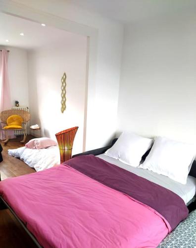 une chambre avec un grand lit avec une couverture rose dans l'établissement Maison des Poules Roses, à Pierrelaye