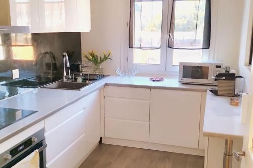 une cuisine blanche avec un évier et un micro-ondes dans l'établissement Maison des Poules Roses, à Pierrelaye