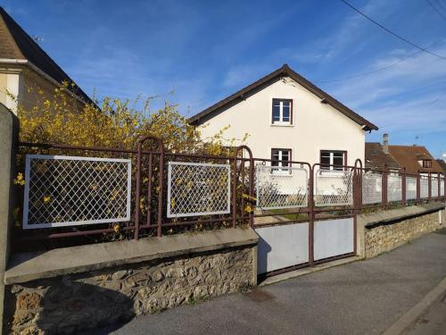 a fence in front of a white house at Maison des Poules Roses in Pierrelaye