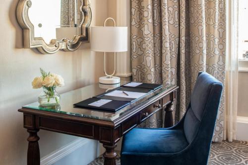 a desk with a blue chair and a mirror at The Roosevelt Hotel New Orleans - Waldorf Astoria Hotels & Resorts in New Orleans