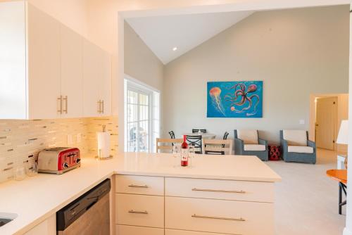 a kitchen with white cabinets and a living room at Colibri Court Antigua in Jolly Harbour