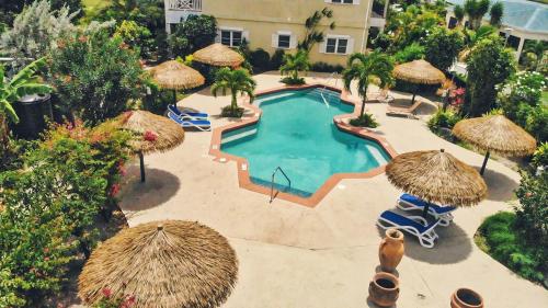an overhead view of a swimming pool with straw umbrellas at Colibri Court Antigua in Jolly Harbour