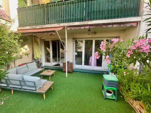 - une terrasse avec un canapé, une table et quelques fleurs dans l'établissement Appartement Boulogne avec terrasse, à Boulogne-Billancourt
