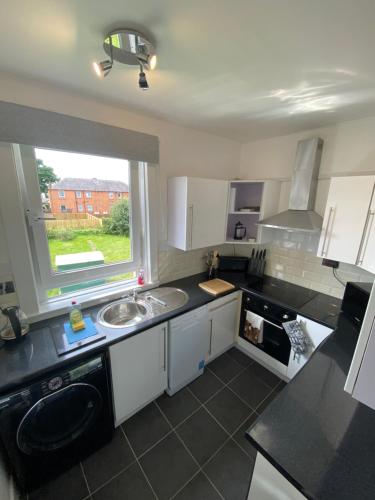 a kitchen with a sink and a window at Edinburgh City Centre & Airport 2 Bedroom Apartment in Edinburgh