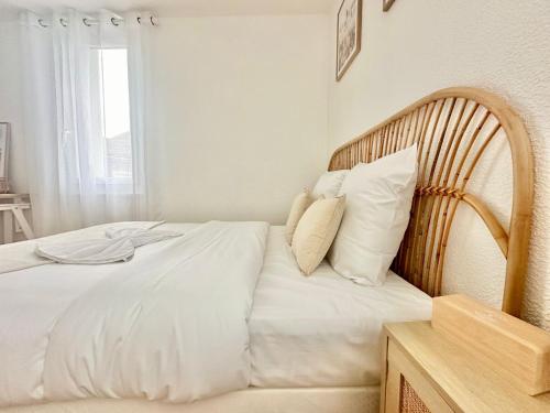 une chambre avec un lit avec des draps blancs et des oreillers dans l'établissement Les Arènes, zen et moderne, à Limoges