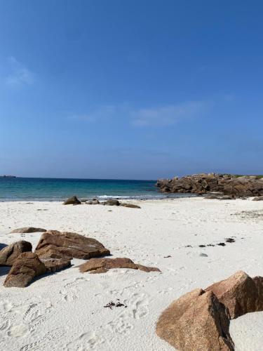 a sandy beach with rocks and the ocean at La légende Men Marz 1er étage- Centre-ville Brignogan-Plages , 300 m des plages in Brignogan-Plages