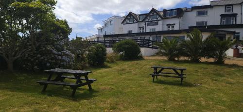 two picnic tables in the grass in front of a building at Sunrise Hotel in Shanklin