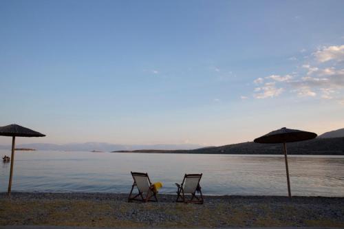 two chairs and umbrellas on a beach with the water at Nerissa Seafront apartment in Itea