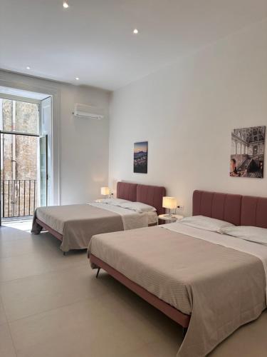 a bedroom with two beds and a window at Blu Parthenope a Spaccanapoli in Naples