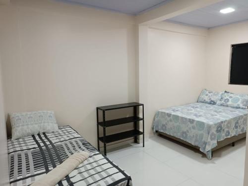 a bedroom with two beds and a tv on the wall at Cattarino Dormitórios in Jardim