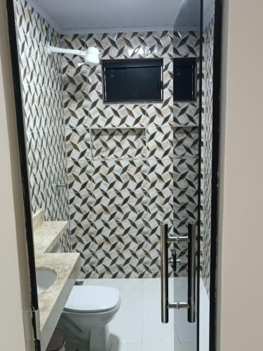a bathroom with a toilet and a tv on a wall at Cattarino Dormitórios in Jardim
