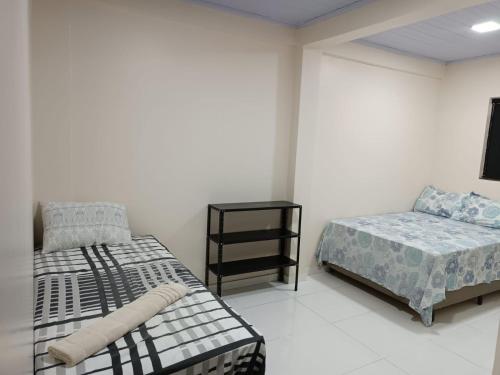 - une chambre avec 2 lits et une table de nuit dans l'établissement Cattarino Dormitórios, à Cristalina