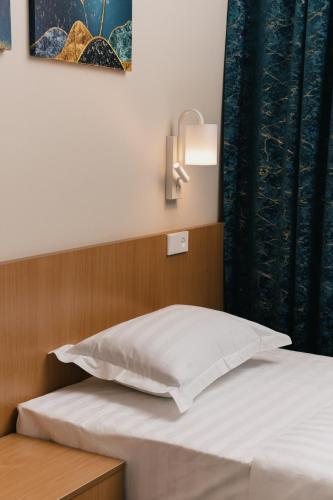 a bed with a white pillow and a lamp on it at Grand Castle Hotel in Urganch