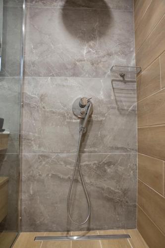 a shower with a hose attached to a stone wall at Nerissa Seafront apartment in Itea