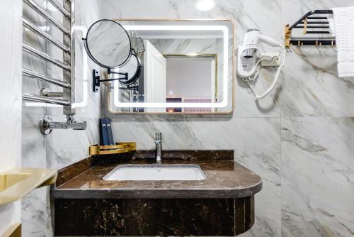 a bathroom with a sink and a mirror at РИМ Grand Hotel in Almaty