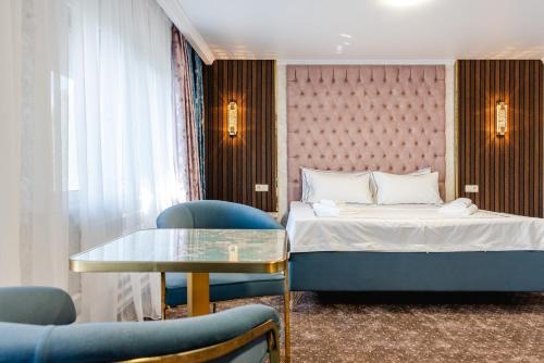a hotel room with a bed and a table and chairs at РИМ Grand Hotel in Almaty