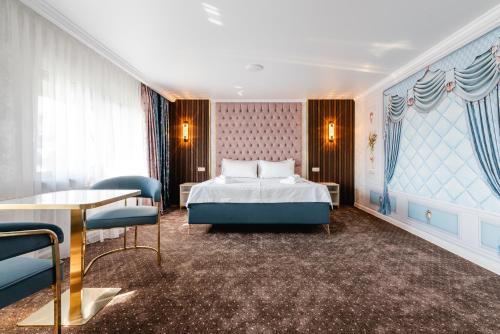 a bedroom with a bed and a table and chairs at РИМ Grand Hotel in Almaty