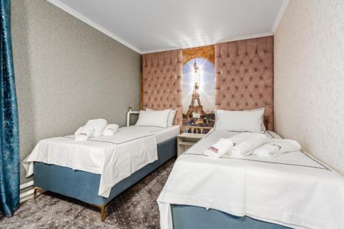 two beds in a room with a tower at РИМ Grand Hotel in Almaty