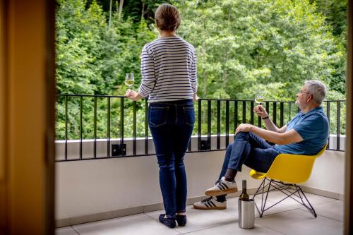 a woman standing on a balcony with a man holding wine glasses at schlossmühle - lean luxury boutique hotel in Glottertal