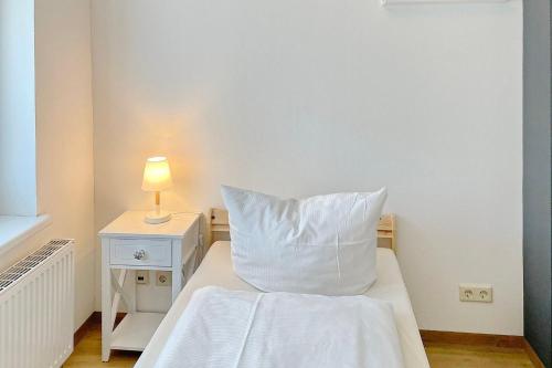 a bed with a white pillow and a lamp on a night stand at Libelle in Lübben