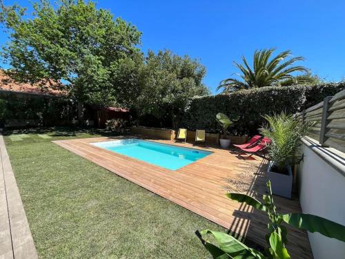une cour arrière avec une piscine et une terrasse en bois dans l'établissement Family home with pool - 5 bedrooms, à Capbreton
