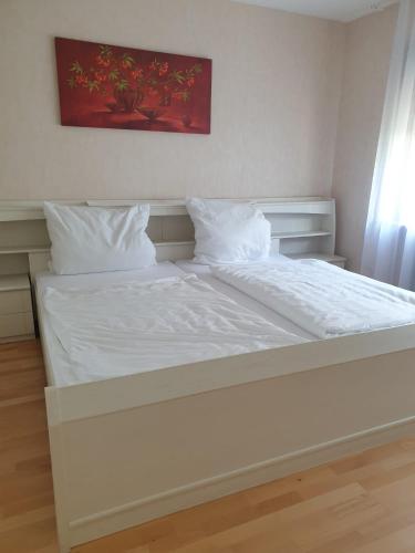 a large white bed with white sheets and pillows at Haus Thea bei Stuttgart in Leonberg