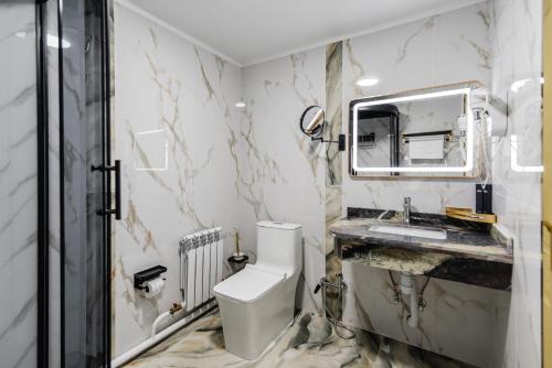 a bathroom with a toilet and a sink and a mirror at РИМ Grand Hotel in Almaty