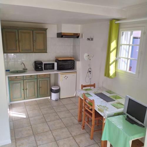 une cuisine avec une table et un comptoir dans l'établissement VAR Studio Rez de chaussée - bord mer et campagne - au calme loin du béton, à La Garde