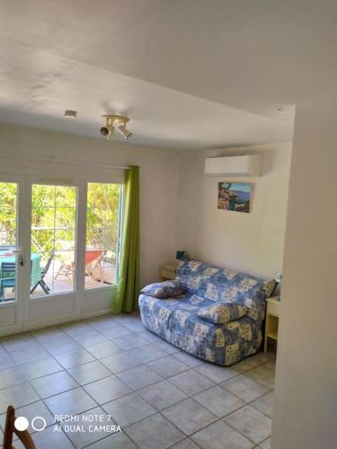 - un salon avec un lit et une porte coulissante en verre dans l'établissement VAR Studio Rez de chaussée - bord mer et campagne - au calme loin du béton, à La Garde