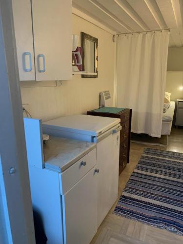 a kitchen with white cabinets and a bed in a room at Strandnära Stuga Lena in Visby