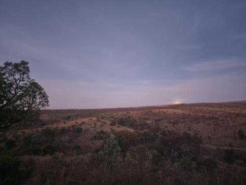a view of a field with the sun in the horizon at Tonquani Bush Chalet in Rustenburg