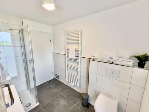 a white bathroom with a shower and a toilet at FeWo Metje - Horumersiel in Wangerland