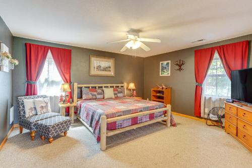 a bedroom with a bed and a tv and red curtains at Picturesque Murphy Cabin with Fire Pit and Views! in Murphy