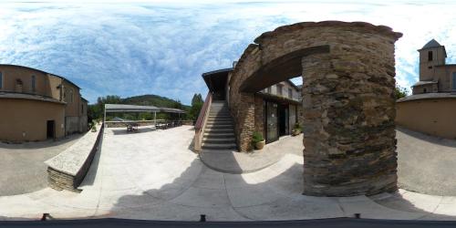 a building with a stone archway in a courtyard at Logis Hôtels - Hostellerie des Lauriers - Hôtel et Restaurant in Alban