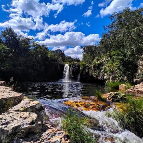 a waterfall in the middle of a river with rocks at Portal Beija-Flor in Alto Paraíso de Goiás