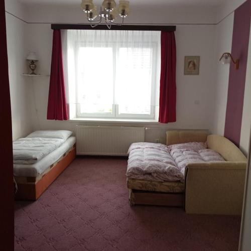 a bedroom with two beds and a window with red curtains at U Melicherů in Suchdol nad Lužnicí