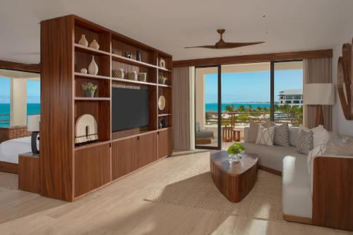 a living room with a television and a living room with the ocean at Secrets Playa Blanca Costa Mujeres - All Inclusive Adults Only in Cancún