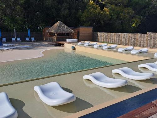 einen Pool mit weißen Liegen und einem Pool in der Unterkunft Titi Happy days in Grand-Bourg