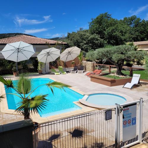 - une piscine avec parasols dans une cour dans l'établissement Les Gîtes de l'Arbousier, à Quissac