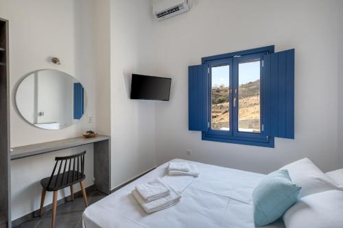 a bedroom with a bed and a mirror and a chair at Sunrise in Livadakia
