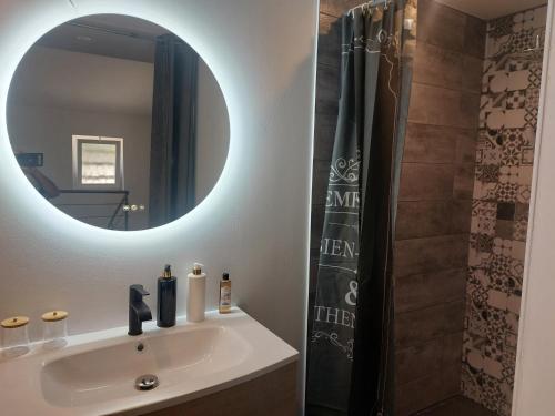 une salle de bain avec un lavabo et un miroir dans l'établissement La Parenthèse, à Moussan