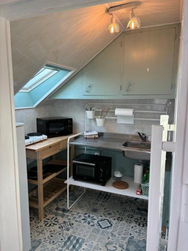 une cuisine avec un évier et un micro-ondes dans l'établissement ASNELLES - Studio à 300m de la mer, à Asnelles